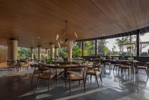 a restaurant with wooden ceilings and tables and chairs at Gdas Bali Health and Wellness Resort in Ubud