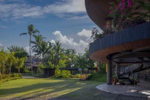 ウブドにあるGdas Bali Health and Wellness Resortのヤシの木が茂る緑の庭のある建物