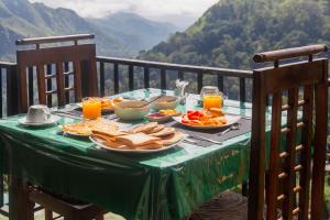 a table with a plate of food and orange juice at New Ella Nature View in Ella