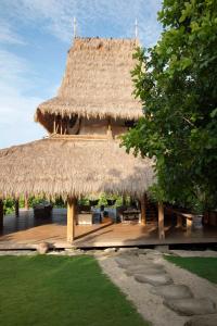 a straw hut with a deck and a grass roof at SumbaFarmHouse in Patiala Bawa