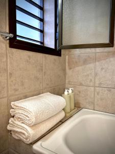 ein Badezimmer mit einer weißen Badewanne, einem Fenster und Handtüchern in der Unterkunft El Nido Bombal in Godoy Cruz