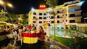 um grupo de pessoas sentadas numa mesa perto de uma piscina à noite em Heaven Hill Hotel & Hot Spring em Cham Ta Lao