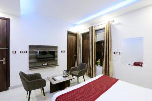 um quarto de hotel com uma cama, uma secretária e cadeiras em Airport Grand Travel Inn em Nova Deli