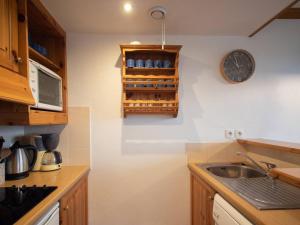 een keuken met een wastafel en een klok aan de muur bij Appartement Valmorel, 2 pièces, 4 personnes - FR-1-291-1007 in Valmorel