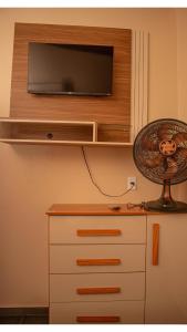 uma televisão numa parede por cima de uma cómoda com uma ventoinha em Pousada Chalés Além do Paraíso em Alto Paraíso de Goiás