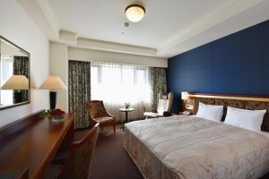 a hotel room with a large bed and a desk at Hotel Crown Palais Chiryu in Chiryu