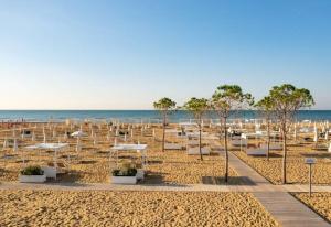 a sandy beach with white umbrellas and the ocean at Charming flat with shared pool - Beahost in Bibione