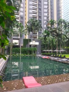 a pool with chairs and palm trees and buildings at Cosy Apartment at KL City Centre in Kuala Lumpur
