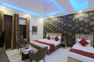 a hotel room with two beds and a desk at Airport Grand Travel Inn in New Delhi