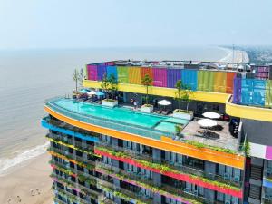an apartment building with colorful balconies next to the beach at Flamingo Ibiza Hải Tiến in Nam Khê