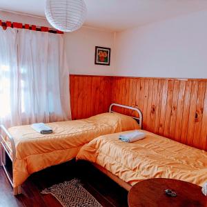 two beds in a room with wood paneling at Hospedaje BRC in San Carlos de Bariloche