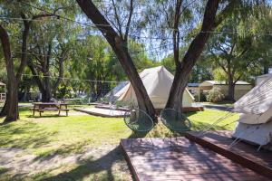 a picnic table and chairs in a park with tents at Busselton Villas and Glamping Village in Busselton