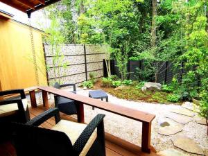 un patio con mesa de madera y sillas en Hanafubuki en Ito