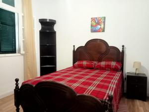 um quarto com uma cama com um cobertor xadrez vermelho em Lombada Villa Comfort em Ponta Delgada