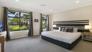 a bedroom with a bed and a large window at 1oak - The Vintage in Pokolbin