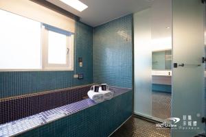 baño con paredes de azulejos azules y lavabo en Ya Nold Hot Spring Hotel, en Jiaoxi