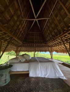 Una cama bajo un techo de paja en un dormitorio en SumbaFarmHouse, en Patiala Bawa