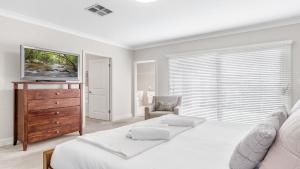 1 dormitorio blanco con 1 cama y vestidor con TV en La Vita - The Vintage, en Pokolbin