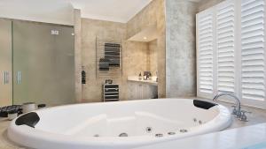 a large white bath tub in a bathroom at The Vintage Manor in Pokolbin
