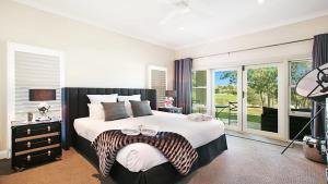 a bedroom with a large bed and a balcony at The Vintage Manor in Pokolbin +12 photos