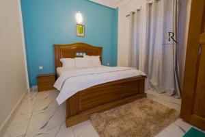 1 dormitorio con cama y pared azul en Résidence Vinelly, en Douala