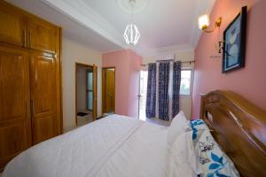 1 dormitorio con 1 cama blanca grande y paredes rosas en Résidence Vinelly, en Douala