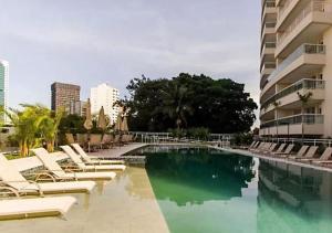 a swimming pool with lounge chairs and a building at 2 quartos no melhor Cond em Pinheiros Thera Faria Lima in Sao Paulo