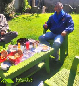 a man sitting at a picnic table with food on it at Luminaire Homestay in Srinagar