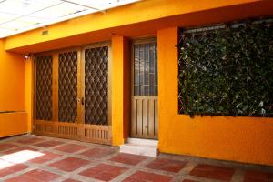 duas portas num edifício laranja com uma cerca verde em Bonito aparta estudio central em Bogotá