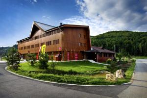 a large building on a grassy area next to a road at Štýlový Apartmán Andrea blízko Snowlandu Valča in Valča