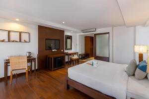 a hotel room with a bed and a dining room at Baan Laimai Beach Resort & Spa - SHA Extra Plus in Patong Beach