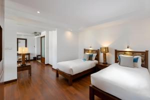 two beds in a room with wooden floors at Baan Laimai Beach Resort & Spa - SHA Extra Plus in Patong Beach