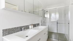 ein weißes Bad mit einem Waschbecken und einer Dusche in der Unterkunft Vino E Golf in Pokolbin