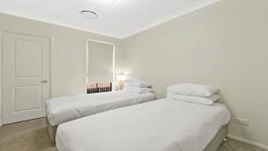 2 Betten in einem Zimmer mit weißen Wänden in der Unterkunft Vino E Golf in Pokolbin