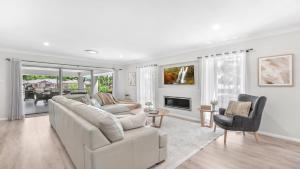 a white living room with a couch and a fireplace at D'Vine Cottage in Pokolbin