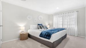 a white bedroom with a bed and a window at D'Vine Cottage in Pokolbin +16 photos