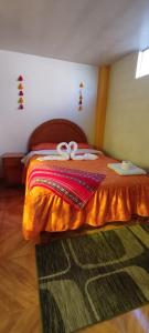 1 dormitorio con 1 cama con edredón de naranja y 2 cintas en HOSTAL ACUARIUS PUNO, en Puno
