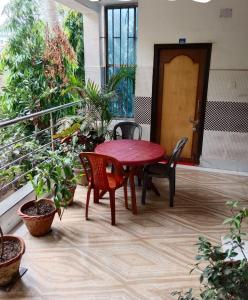 狄哈的住宿－Anjali Guest House，种植了植物的阳台,配有红色的桌椅