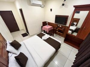 a small room with two beds and a television at Velan Temple View By PPH Living in Palani