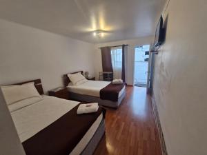 Cette chambre comprend deux lits et une télévision. dans l'établissement Hosteria Piedra Blanca, à Taltal