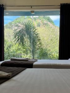 a bedroom with a view of a palm tree from a window at Velan Temple View By PPH Living in Palani