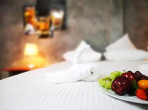 a plate of fruit on a table with a glass of wine at Hotel Vinchenso in Kaduwela