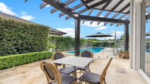 a patio with a table and chairs and a swimming pool at Belleview Hunter in Pokolbin