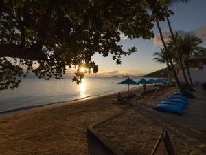 a beach with umbrellas and chairs and the ocean at Explorar Koh Phangan - Adults Only Resort and Spa in Haad Rin