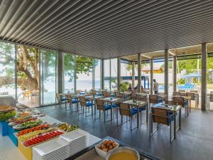 a dining room with tables and chairs and windows at Explorar Koh Phangan - Adults Only Resort and Spa in Haad Rin