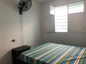 ein Schlafzimmer mit einem Bett und einem Ventilator an der Wand in der Unterkunft Hostal Los Abuelos Colombianos in Cartagena de Indias