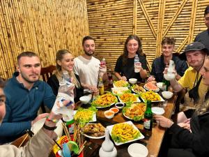 a group of people sitting around a table with food at Viet Hung Hostel - Motorbikes Rental- BUS TICKET in Làng Lap