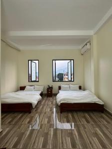two beds in a room with two windows at Viet Hung Hostel - Motorbikes Rental- BUS TICKET in Làng Lap