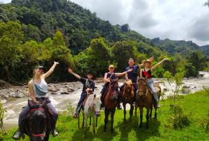 un grupo de personas montando caballos por un río en Terracota Mirador Filandia, en Filandia