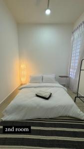 a white bedroom with a bed with a towel on it at The Borneo Suite - Group of 6 - 9 pax in Kota Kinabalu